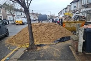 Pile of sand and skip with rubbish on street